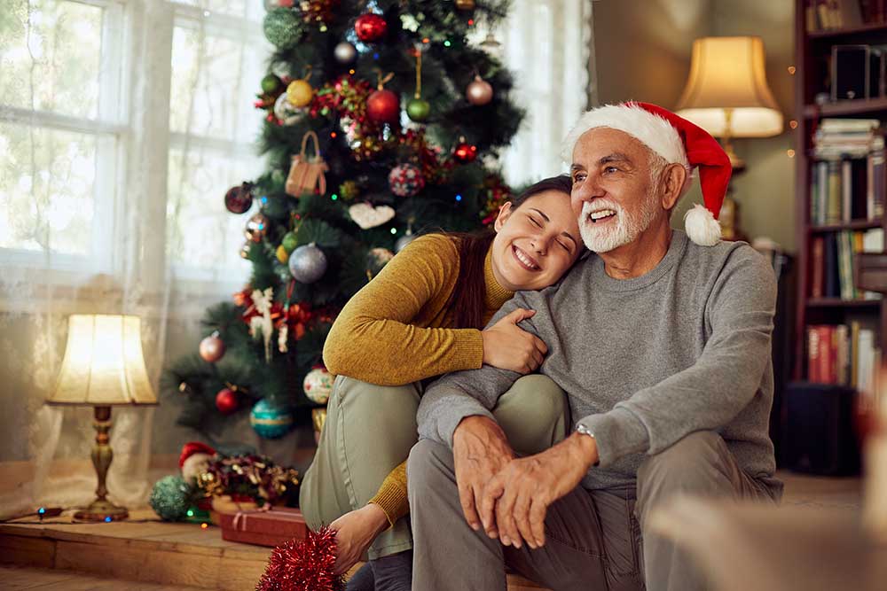 Happy woman embraces her senior father on Christmas day at home.