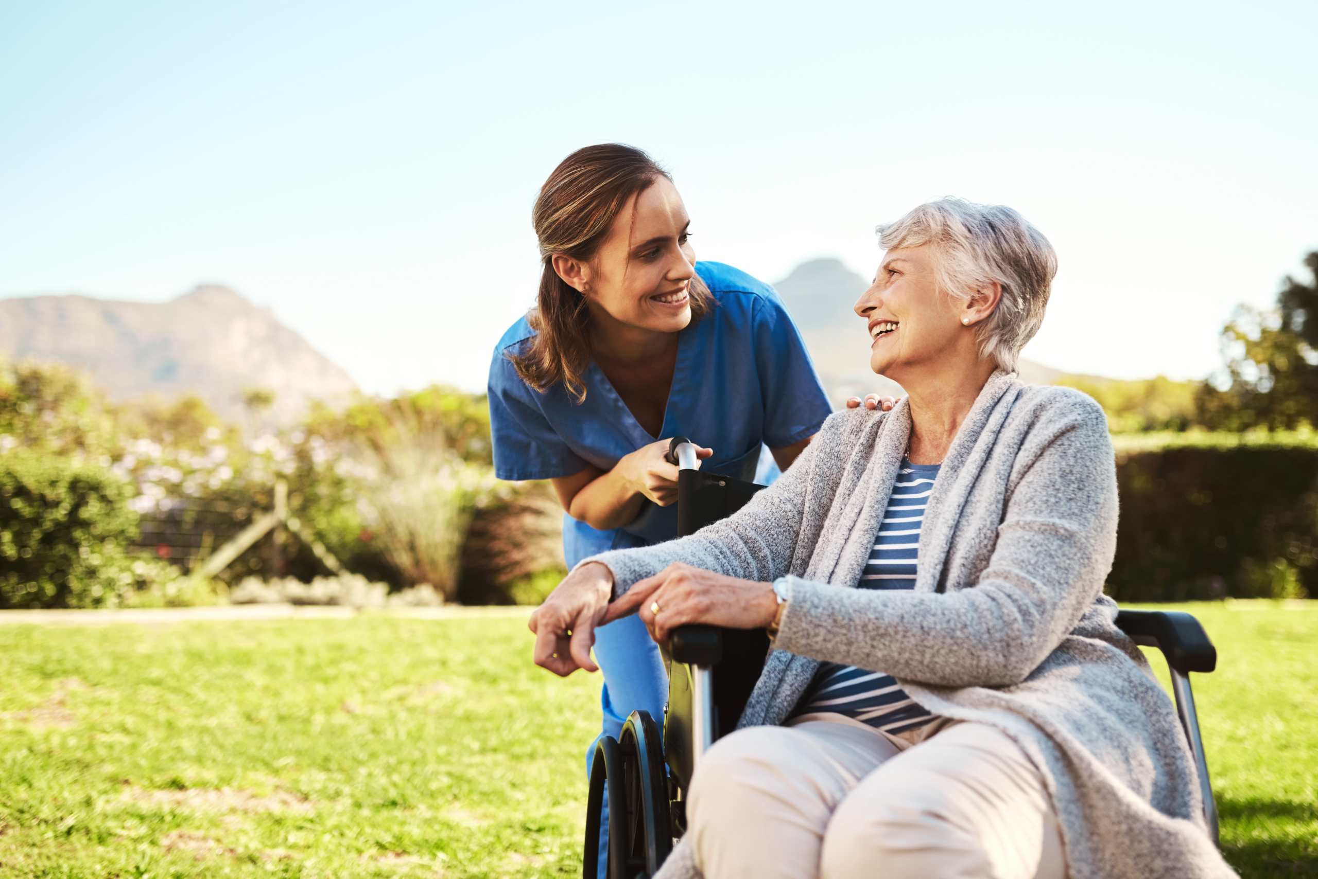 Senior woman, nurse and wheelchair for healthcare support, life insurance or garden at nursing home. Happy elderly female and caregiver helping patient or person with a disability in nature outdoors
